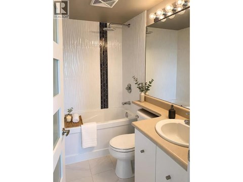 A white bathroom with a toilet, sink, and a shower.
