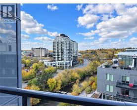 A view from a balcony overlooking a city with apartment buildings and trees in autumn colors.