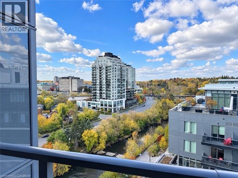 A view from a balcony overlooking a city with apartment buildings and trees in autumn colors.