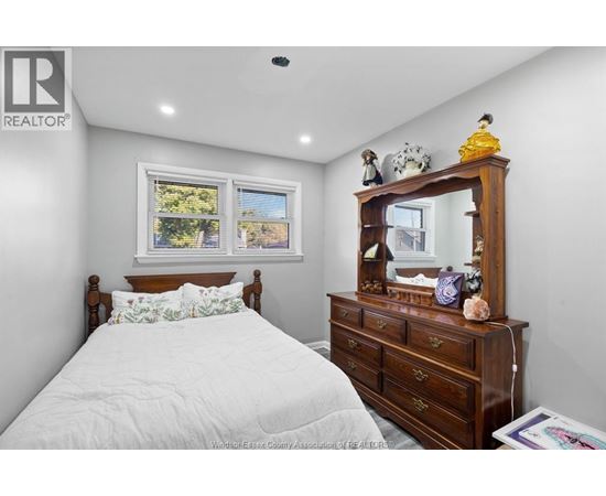 A bedroom with a bed, dresser, and mirror.