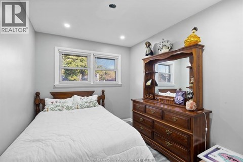 A bedroom with a bed, dresser, and mirror.