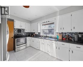 A kitchen with white cabinets and a black counter top.