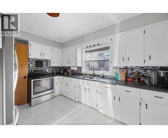 A kitchen with white cabinets and a black counter top.