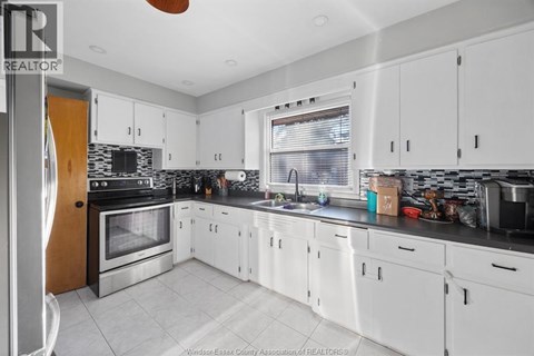 A kitchen with white cabinets and a black counter top.