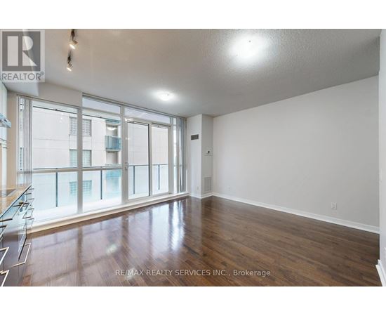 A spacious room with wooden floors and large windows.