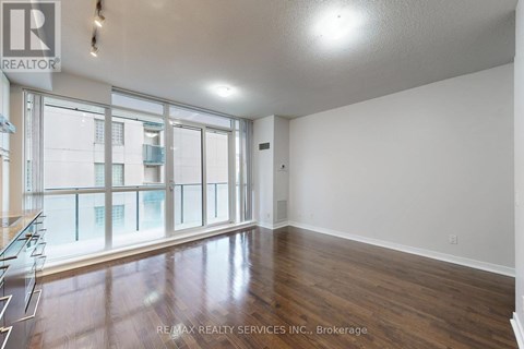 A spacious room with wooden floors and large windows.