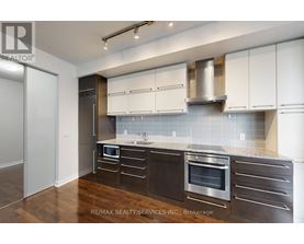 A modern kitchen with dark wood cabinets and stainless steel appliances.