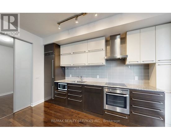 A modern kitchen with dark wood cabinets and stainless steel appliances.