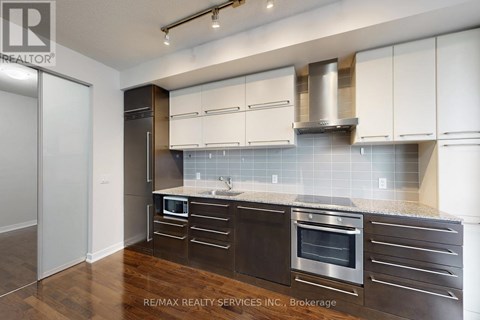 A modern kitchen with dark wood cabinets and stainless steel appliances.
