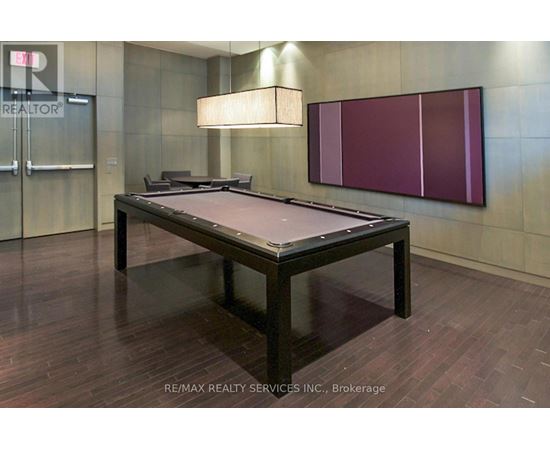 A pool table in a room with a wooden floor and a purple wall.