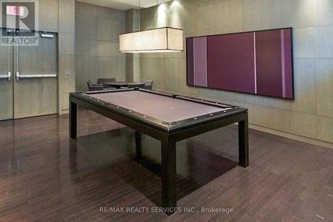 A pool table in a room with a wooden floor and a purple wall.