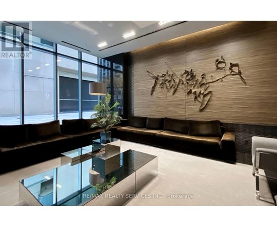 A modern living room with a glass table and a brown couch.