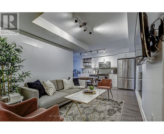 A modern living room with a grey sofa, a coffee table, and a television mounted on the wall.