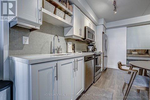 A kitchen with white cabinets and a grey backsplash.