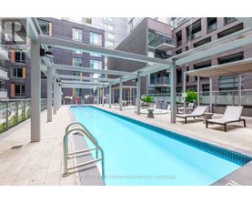 A swimming pool in a residential area with lounge chairs and a walkway.
