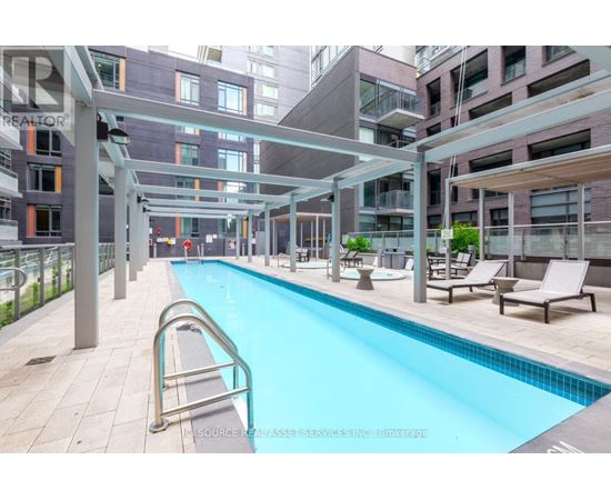 A swimming pool in a residential area with lounge chairs and a walkway.