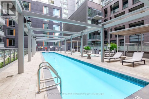 A swimming pool in a residential area with lounge chairs and a walkway.
