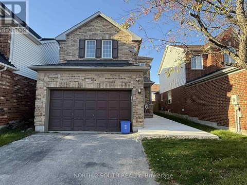 A house with a garage door and a blue bin in front of it.