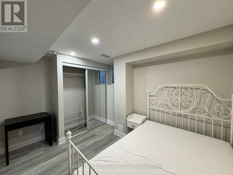 A bedroom with a white bed and a grey wall.