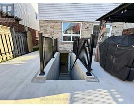 A concrete staircase with a metal railing leads down to a basement entrance.
