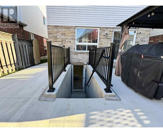 A concrete staircase with a metal railing leads down to a basement entrance.