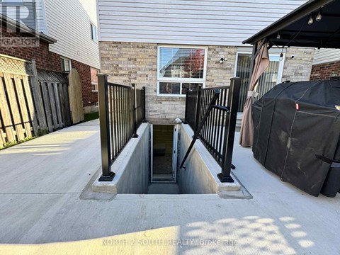 A concrete staircase with a metal railing leads down to a basement entrance.