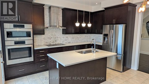 A modern kitchen with dark brown cabinets and stainless steel appliances.