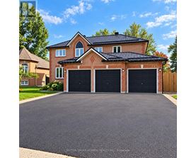 A house with a brick facade and a black roof has a driveway in front.