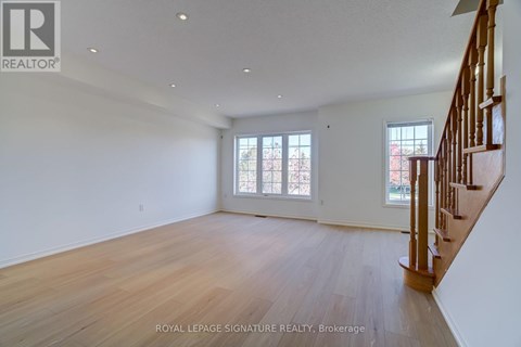 A spacious room with wooden floors and a staircase.