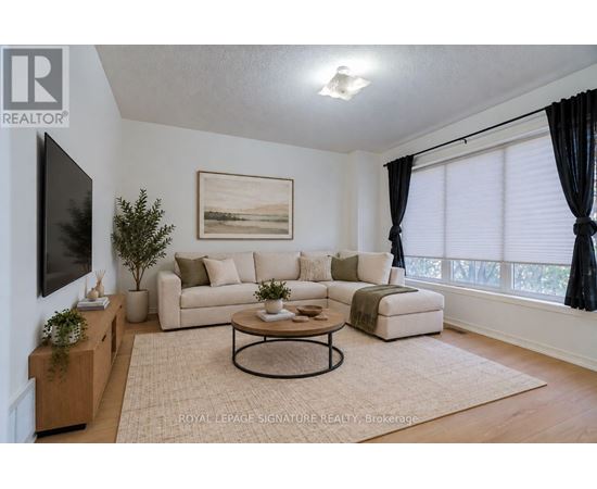 A living room with a couch, a coffee table, and a painting on the wall.
