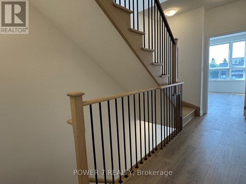 A staircase with a wooden handrail and black metal balusters.
