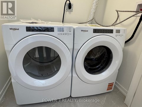 Two white Whirlpool washing machines in a laundry room.