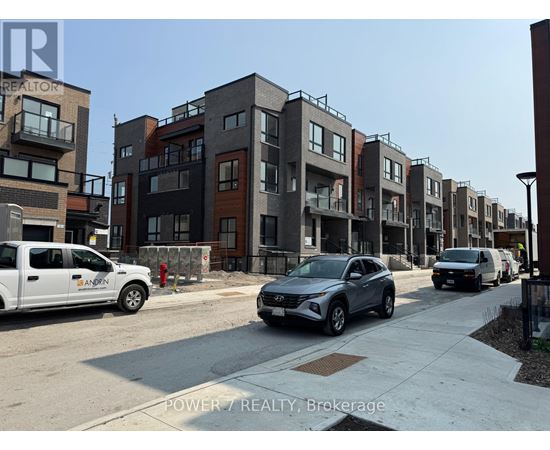 A row of modern townhouses with cars parked in front.