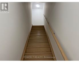 A staircase with wooden steps and a white wall on one side.