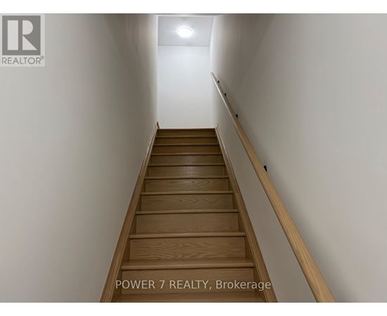 A staircase with wooden steps and a white wall on one side.