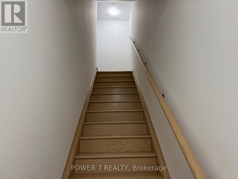 A staircase with wooden steps and a white wall on one side.