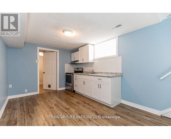 A kitchen with white cabinets and a wooden floor.