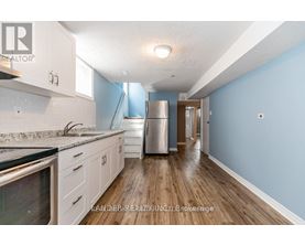 A kitchen with a refrigerator, sink, and cabinets.