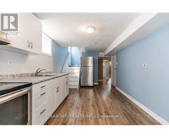 A kitchen with a refrigerator, sink, and cabinets.