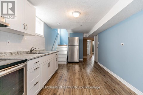 A kitchen with a refrigerator, sink, and cabinets.