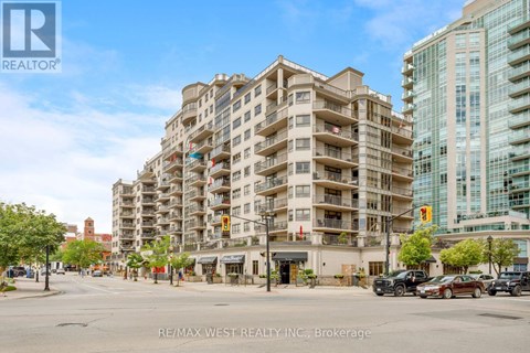 A large apartment building is situated on a street corner with cars parked in front.