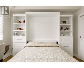 A bedroom with a large bed and shelves with decorative items.