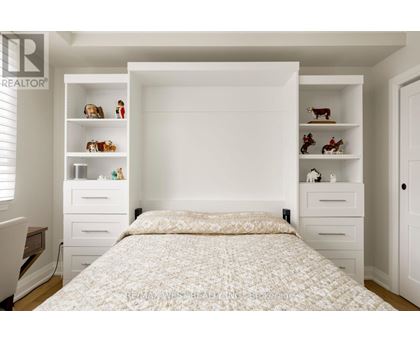 A bedroom with a large bed and shelves with decorative items.