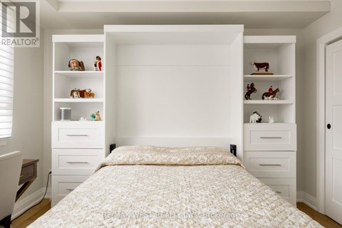 A bedroom with a large bed and shelves with decorative items.
