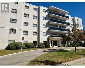 A large white apartment building with a sign that says REALTOR.