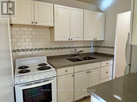 A kitchen with white cabinets and a stove top oven.