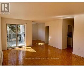 A spacious room with a wooden floor and white walls, with a sliding glass door leading outside.