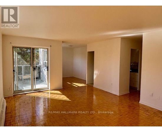 A spacious room with a wooden floor and white walls, with a sliding glass door leading outside.