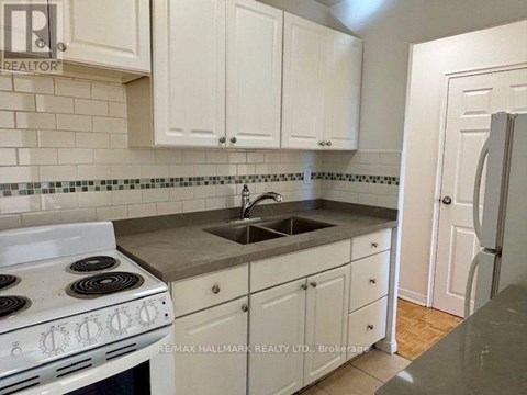 A kitchen with white cabinets and a white stove top oven.