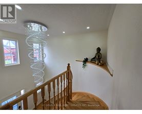 A chandelier hangs from the ceiling in a room with a wooden staircase.